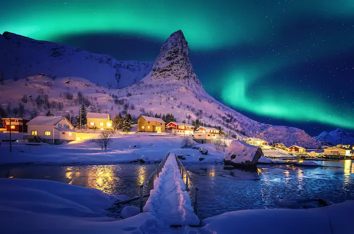 vue sur un village de laponie dans la nuit avec des aurores boréales