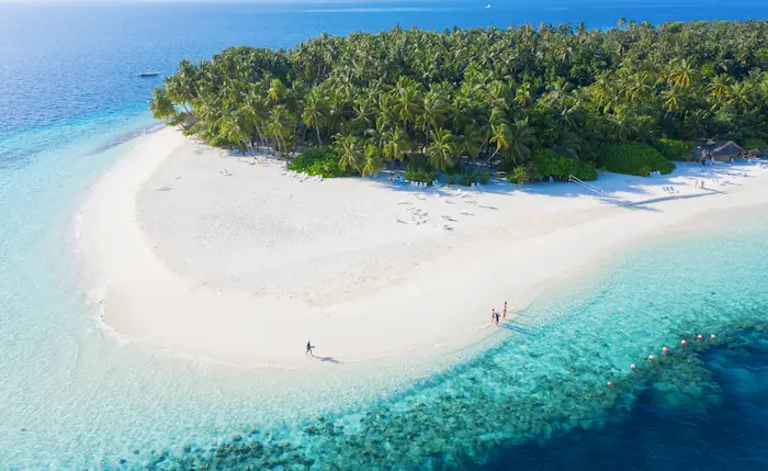 vue aérienne d’une plage de sable blanc et d’une mer turquoise aux Maldives
