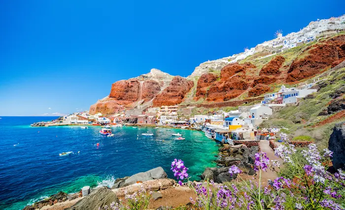 vue sur un village de la côte de santorin avec des falaises rouges et une mer turquoise